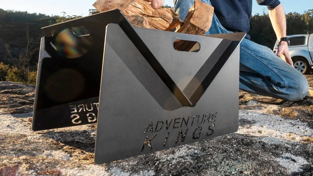 Adventure Kings portable camping fire pit setup on rocky terrain.